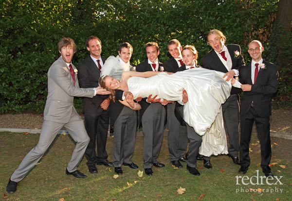 Groom with best men and ushers holding the bride